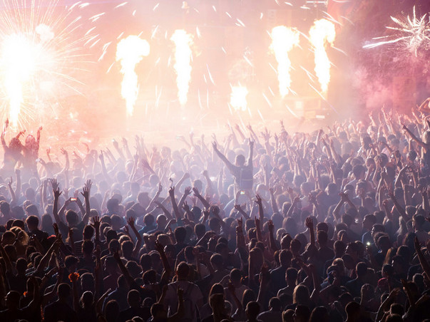 Cheering crowd at concert in front of stage with pyrotechnics