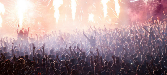 Cheering crowd at concert in front of stage with pyrotechnics