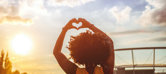 Young African American woman at summer holi festival make heart