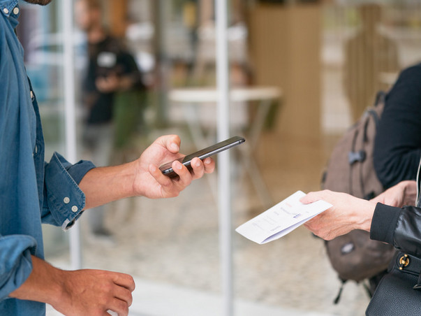 man holding smartphone in front of person in black jacket